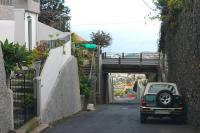 The old rack railway from Funchal to beyond Monte has been turned into a road known variously as Rue de Comboio, Caminho de Comboio and Ave de Comboio (basically Railway Rd). Houses now line much of the route but there is evidence of its former use at various points such as this overbridge in the suburbs of Funchal. View south down the steep hill towards the centre of the city.   <br><br>[Mark Bartlett 23/03/2013]