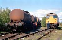 Indulging in a little gravity shunting at the James Watt Dock, Greenock in 1988. The train has drawn out of the United Molasses depot and then reversed up the tight curve towards Ladyburn. Then brakes applied. Loco comes off and runs back into James Watt dock sidings by the molasses depot. Train is dropped downhill past the points and locomotive then joins train for the second trip up to Ladyburn, this time at the other end. <br><br>[Ewan Crawford 09/05/1989]