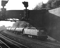 An unidentified Brush Type 4 brings an eastbound train of 100T bogie oil tanks under Addingford Lane Bridge at the west end of Horbury cutting. Thought to have been taken on 12th May 1977.<br><br>[Bill Jamieson 12/05/1977]