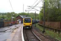 The tightly curved platform at Dinting station on the line to Glossop with a Manchester - Hadfield via Glossop service on 12 May 2013. Off picture left is the remaining platform on the line to Hadfield which once saw express passenger and heavy coal trains on the Woodhead route. In the trees on the right are the remains of the Manchester bound platform on the Glossop line.<br><br>[John McIntyre 12/05/2013]