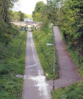 The former Eskbank station site on 22 May 2013, with the old footbridge and most of the platform structures now demolished and removed [see image 5740]. View north from the A6094, with the station building behind the trees at the top of the ramp and the bus in the background heading east along the A768.<br><br>[John Furnevel 22/05/2013]