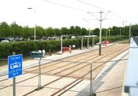 The new tram stop at Gyle Centre seen from the road in June 2013. Car parking for the Gyle shopping centre covers the area beyond the hedge. View is from South Gyle Broadway towards Edinburgh Park.<br><br>[John Furnevel 07/06/2013]