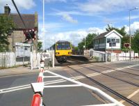 A Leeds to Morecambe service at Bare Lane on 15 June 2013. The signalbox on the right is now out of use with lines and level crossing controlled by Preston PSB. As there is no PIS on the platforms to advise passengers which platform their train will arrive at, a member of staff is using the old box as a base from which to direct passengers until displays are installed.<br><br>[John McIntyre 15/06/2013]