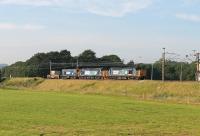 The evening DRS train from Sellafield to Crewe, and the morning run in the opposite direction, are often used to transfer locomotives as well as flasks. Backlit by the July evening sun, two DRS Class 37s head south between Garstang and Brock hauling a Class 20 and a single flask wagon.<br><br>[Mark Bartlett 09/07/2013]