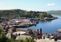 View over Oban pier and station from McCaig's Tower on 10 July. The area of the pier adjacent to the station has become a mini-mall with shops, cafes and restaurants.<br><br>[John Gray 10/07/2013]
