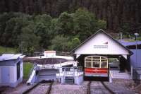 Track-level view down the 1 in 4 gradient at the Obstfelderschmiede terminus of Germany's unique funicular Oberweissbacher Bergbahn in the forested hills of the Thuringer Wald on 28 June 2013. The sloping split-level passenger coach is waiting to depart for Lichtenhain. The turntable to the left allows interchange of standard-gauge rolling stock (carried ' piggyback' on the 1.8m gauge funicular) from the Schwartzatalbahn branch, which is a right angles to the funicular behind the station building.<br><br>[David Spaven 28/06/2013]