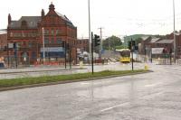 North of the former Oldham Mumps station the railway ran on an embankment and crossed the road on a series of bridges. The building on the left featured in a former mystery image taken in 1968 [see image 37965]. By July 2013 the embankment and bridges have been removed during conversion to Metrolink. This busy road crossing will go when trams start running through Oldham town centre and the original alignment between Mumps and Werneth is abandoned. The new tram line towards the town centre can be seen in front of the red brick building.<br><br>[John McIntyre 31/07/2013]