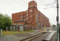 Briar Mill dominates the scene at Shaw and Crompton on 31 July 2013. The photograph was taken from what would have been the station's Rochdale platform. The old station has now been replaced by a tram stop, built on the other side of the level crossing [see image 44105].<br><br>[John McIntyre 31/07/2013]