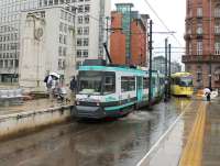 Quite a bow wave is created by the rear bogie of Metrolink 1022 as it leaves St. Peter's Square, indicating that all is perhaps not as it should be with the drains in this city centre tram station. This section now carries trams to Altrincham, Eccles and East Didsbury and so the performance was repeated every few minutes on this very wet day.<br><br>[Mark Bartlett 31/07/2013]