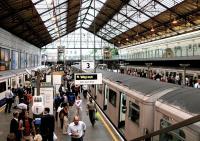 View west over District Line platforms 3 and 4 at Earls Court on the morning of 16 June 2004. A Wimbledon train is about to leave 4 while an Ealing Broadway service has recently arrived at 3. Commuters are rushing to cross the bridge to catch the Edgware Road train standing at platform 1 as there wouldn't be another for almost 6 minutes.<br><br>[John Furnevel 16/06/2004]