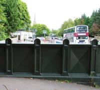 The view east towards Dalkeith from Cemetery Road bridge in July 2013 [see image 39723]. The trackbed has been obliterated from this point, with a car wash now located directly ahead, behind which are the premises of the local rugby club. Beyond that is the station site itself, currently being redeveloped as a supermarket. On the right a Lothian no 3 bus heads towards Dalkeith town centre, with the spire of St John's Church dominating the background.<br><br>[John Furnevel 25/07/2012]