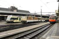 Three different operational gauges make Montreux station unique in Switzerland. All the trains in this view are of metre gauge but under the canopies are the SBB standard gauge platforms and just off picture to the right are the 800mm tracks of the Rochers de Naye cog railway. MOB GDe4/4 6005 leaves with the daily <I>Chocolate Train</I>, a tourist service, while railcars 7004 and 1007 await duties.<br><br>[Mark Bartlett 10/09/2013]