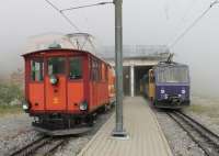 The cog railway summit station at Rochers de Naye (6463 ft) is just in the cloud as 303 <I>Villeneuve</I> waits to return to Montreux. Alongside the two-car unit is rack locomotive No. 2, dating from 1909 but rebodied <I>old style</I> in 1986. No. 2 heads an engineering vehicle that is also fitted with fire fighting equipment. <br><br>[Mark Bartlett 09/09/2013]