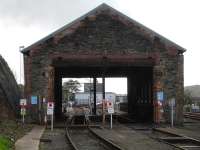 Looking through the former 89C Machynlleth steam shed on 17 October 2013. View is west with the new ERTMS signalling centre building framed by the entrance openings. Beyond that is the roof of the main station building. The steam shed pits are used for deep cleaning of engines and bogies, with a lightweight bridge structure outside the west end for roof cleaning.<br><br>[David Pesterfield 17/10/2013]