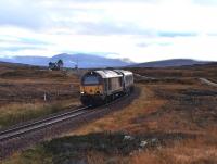 67009 has just passed Corrour Summit on 26 October 2013 and is on the descent to Loch Treigwith the northbound Caledonian Sleeper for Fort William. In the background is the remote Corrour Station and signal box, standing in the midst of bleak moorland.<br><br>[John Gray 26/10/2013]