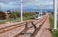 An Edinburgh tram about to cross over east of Edinburgh Park station on 8 October prior to running back to Gogar Depot. Meantime a westbound DMU passes on the embankment in the background. <br><br>[Bill Roberton 08/10/2013]