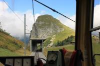 Descending from the Rochers-de-Naye summit a rack railway train approaches the isolated station at Jaman, just visible through the right hand window. In between, on this exposed section of track, are two shelters that the train passes through. Jaman station, despite its remote location, has a cafe bar for travellers and hikers.<br><br>[Mark Bartlett 09/09/2013]