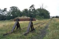 The end of the line..  Following final closure of the Maldon-Witham line in 1966, a half mile length was retained at the Witham end to serve the Rom River factory.  This is the rural setting of the end of that stub, well beyond the factory siding, in 1977. The pasture to the left was transformed into a dense housing estate by 1980 and this buffer stop ended its days amidst suburbia.<br><br>[Mark Dufton 28/08/1977]