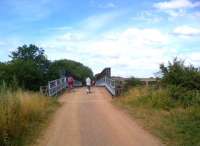 Looking North towards the station site at Irthlingborough [see image 44129], which was just beyond the long 1930's concrete road bridge in the right background. It is clear that the bridge up ahead is not an original railway over river bridge. The ramp angle is a bit of a giveaway; on closer inspection, it seems to be an ex-military Bailey bridge.<br><br>[Ken Strachan 26/07/2013]