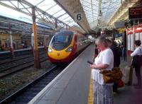 A Northbound Pendolino proudly shows off the Virgin version of blood and custard at Crewe in July 2013. The roof trusses are perhaps more elegant. Drivers must surely be pleased to see everyone standing behind the yellow line as requested.<br><br>[Ken Strachan 29/07/2013]