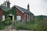 The former station at White Colne in June 1976, looking towards Earls Colne. Tickets used to be issued from the porch, but latterly the platform was behind the camera across a minor road. The rubble in the foreground marks the site of the crossing keeper's hut, which had recently been taken away for rebuilding on the Colne Valley Railway. The main building has survived in good order as the village hall. [Ref Query 6617]<br><br>[Mark Dufton 06/06/1976]
