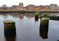 View north in December 2013 over the remains of the bridge which carried the branch to Ayr's south harbour. Taken from the terrace of <I>The Waterfront</I> bar/ restaurant which is built across the trackbed. On the far bank, the gap in the wall visible under the radio mast is where the track emerged from the goods yard, now also built over. [See image 36905]<br>
<br><br>[Colin Miller 10/12/2013]