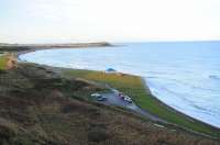 Looking down on the site of Golf Club House Halt, Banff, on 2nd January 2014. View west along the branch towards the junction at Tillynaught [see image 6729]. The railway has gone, but  53 years on the beach shelters remain  (recently restored). At the Halt site a small explosives magazine, and some iron GNoSR fence posts remain beside the trackbed. The car park has more modern occupants!<br><br>[Brian Taylor 02/01/2014]