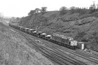 40038 south of Goose Hill Junction box in February 1977 with ballast in a variety of Engineer's wagons. They are all equipped with the vacuum brake and the train is running as a fully fitted working with the loco displaying the correct class 6  headcode discs, despite the requirement for this having been abolished a year earlier. The vantage point gives a good view of the facing crossover arrangement between the ex-MR and ex-L&Y lines.<br><br>[Bill Jamieson 12/02/1977]