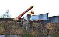 View south across the River Dulnain towards Broomhill station on 14 February 2014 as the Colas Crane approaches the bridge with the second girder. <br><br>[John Gray 14/02/2014]