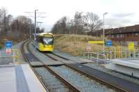 An interesting civil engineering solution. The Oldham Loop line climbed through South Chadderton on an embankment without a station. On conversion to Metrolink a tram stop was built but at street level with the trams dropping steeply down on either side before climbing back to the original formation. In this view looking towards Oldham Tram 3020 drops down to the new halt passing what remains of the original L&YR railway embankment. <br><br>[Mark Bartlett 13/02/2014]