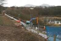 View south along the now closed <I>Black Path</I> towards the <I>Red Bridge</I> linking Galashiels and Tweedbank on 26 February. The JCB is standing at the point where the path and the old Waverley trackbed split, with the former climbing to join Winston Road (from which the photograph was taken) and the latter continuing north under the road towards Galashiels station [see image 46466].<br><br>[John Furnevel 26/02/2014]