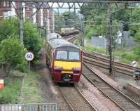 An early afternoon Airdrie - Balloch service departs westbound from Dalmuir station in July 2005. The train is about to pass what will become the next city bound service, currently in the holding siding waiting to run back into the station.<br><br>[John Furnevel 27/07/2005]