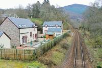 Looking south from the road bridge over the site of Killiecrankie Station (closed 1965). The A9 road can be seen in the background, high above the gorge. The houses alongside the old station are a recent construction [See image 14998] <br><br>[Mark Bartlett 05/04/2014]