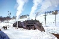 The Waverley Route experienced one of the biggest challenges of its existence when the country suffered sub-zero temperatures from late December 1962 through to early March 1963. By 23rd February 1963, an 18-day snow blockage had been cleared, but only for single-track operation. Here, seen from a morning train from Edinburgh to Carlisle working 'wrong line' through Riccarton Junction, unidentified Standard Class 2 and Class 4 2-6-0s - coupled tender to tender on the Up line - take a break from snowploughing duties. <br><br>[Frank Spaven Collection (Courtesy David Spaven) 23/02/1963]