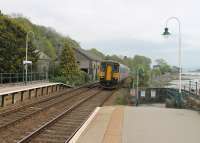 153301, on a Lancaster to Barrow service, leans towards the sea as it slows for Grange-over-Sands station on 28 April. The single unit is passing the operational signal box and the old goods shed, now in commercial use. Services on this line are shared between the Northern and TransPennine Express franchises.<br><br>[Mark Bartlett 28/04/2014]