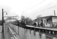 Hurlford shed's 45124 causes a stir amongst passengers on the platform at Williamwood awaiting their usual emu on a wet Saturday 11 April 1964. The Black 5 is on its way to Kings Park with a football special from Kilmarnock.<br><br>[John Robin 11/04/1964]