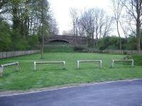 A view of the partially in-filled road overbridge and wide throat at the east end of the former Masham terminus station and goods yard complex in April 2014. The location is now a camping and caravan centre [see image 34893]. [Ref query 6949]<br><br>[David Pesterfield 21/04/2014]