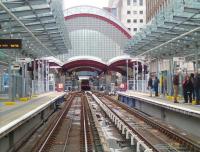 View south from a train entering West India Quay on the Docklands Light Railway on 26 May. Directly ahead (and very close) is Canary Wharf station with a DLR train to Stratford in the centre road.<br><br>[John Thorn 26/05/2014]