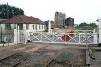 Back in July 1990, when this photo was taken, the level crossing gates at North Elmham were in pristine condition, having been very recently repainted and overhauled. This posed some interesting questions for British Rail, given that the line had closed completely 18 months earlier and the granary that supplied the last freight traffic lies in ruins in the background. Sadly, the gates did not receive any further care and were left to slowly deteriorate, pending reopening of the line one day. The north gate (nearest) was the first to collapse nineteen years later and was replaced by a metal version.<br><br>[Mark Dufton /07/1990]