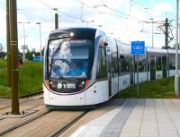 'Shades' definitely required by tram drivers heading east from Edinburgh Airport on the morning of 12 June 2014. A city bound tram makes its first stop at Ingliston Park and Ride in bright sunshine. Note the original livery has already been changed to match Edinburgh's rebranded bus fleet. The official colour description is 'madder and white' although it had been suggested that 'madder and madder' would have been more appropriate... [See image 3925]<br><br>[John Furnevel 12/06/2014]