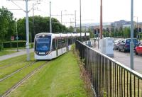 An airport bound Edinburgh tram comes off the level crossing over South Gyle Broadway on 11 June 2014 as it slows for the stop at Gyle Centre.<br><br>[John Furnevel 11/06/2014]