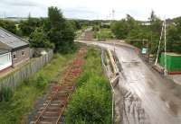 The remains of Millerhill station looking south along the trackbed of the Waverley route on 26 June 2014. The temporary road access is in connection with the construction of a Biogen food waste recycling plant being built at the north end of the old yard. The Glencorse Branch, latterly serving Bilston Glen Colliery, turned west in the middle distance [see image 5547].<br><br>[John Furnevel 26/06/2014]