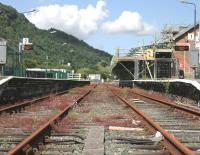 Repairs to the roof of the Cambrian station at Porthmadog, which blew off in the storms in February 2014, seen looking west on 6 July, with nature attempting to reclaim the trackbed. Gwynedd Council has announced that the line, currently closed from Harlech to Pwllheli because of problems with the rebuilding of the Pont Briwet, should reopen by 1st September.<br><br>[Colin McDonald 06/07/2014]