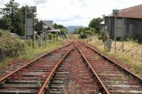 Looking east from the Stryd Fawr level crossing on the Cambrian Coast line on 6th July, with Porthmadog main line station behind the camera. The Welsh Highland Railway heritage station is on the left. The disused looking main line has been closed since December 2013 because of problems with the rebuilding of the Pont Briwet at Penrhyndeudreath.<br><br>[Colin McDonald 06/07/2014]