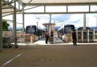 A quiet period at Edinburgh Airport tram terminus on Sunday 13 July 2014 in a picture featuring 4 ticket machines, 3 staff, 2 trams and no passengers.<br><br>[John Furnevel 13/07/2014]