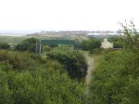 View south east from the A1086 road bridge, north of Hartlepool, along the old route from Castle Eden junction that met the Durham coast line here; and which is now part of the Three Rivers National Cycle Route 14 between Haswell & Hartlepool. The former station of Hart 1873-1953) stood just south of where the lines met. The coast line can just be seen running through the footbridge before, above the tree to its right, it can be seen continuing forward of view towards the Headland on the northern edge of Hartlepool; where it will again turn south towards the town centre. <br><br>[David Pesterfield 13/07/2014]