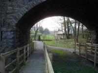 View west along the trackbed of the abandoned section of the Wensleydale line looking towards Garsdale through the road overbridge from Hawes station in April 2014. [Ref query 11273] <br><br>[David Pesterfield 21/04/2014]