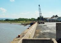 A view along the East Wall at Glasson Dock. Rails formerly ran along the line now covered by the sea defence wall and continued round to join those from the dock itself at the point on the far left of the picture where a building can be seen. That marks the site of the long demolished passenger station. Ships still load and unload at this riverside quay. Picture on private land taken with kind permission of Port of Lancaster Commissioners. <br><br>[Mark Bartlett 24/07/2014]