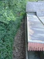 View looking north from High Street overbridge along the overgrown track at the former Llangefni station, showing the platform canopy still in situ, but with a wall along the platform edge for the occupied station house. A rail can just be seen in the clear area at upper centre of the view.<br><br>[David Pesterfield 23/07/2014]