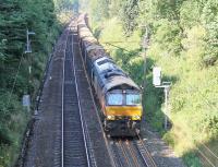 Bright July afternoon sunshine, but most of the cutting on Lancaster bank is still in shadow. A Colas Class 66 powers up the 1:82 with the Carlisle to Chirk log train. <br><br>[Mark Bartlett 22/07/2014]